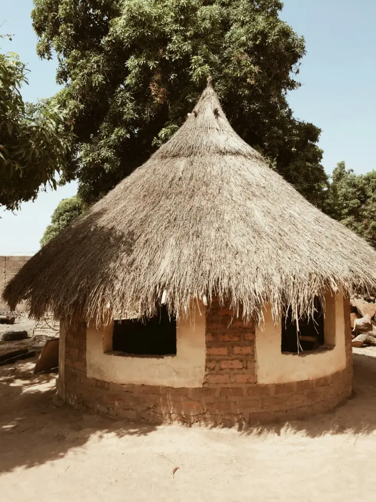 a hut with a thatched roof and brick walls
